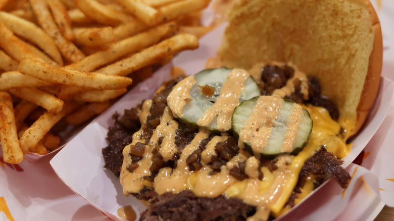 smash burger with sauce, pickles, and fries