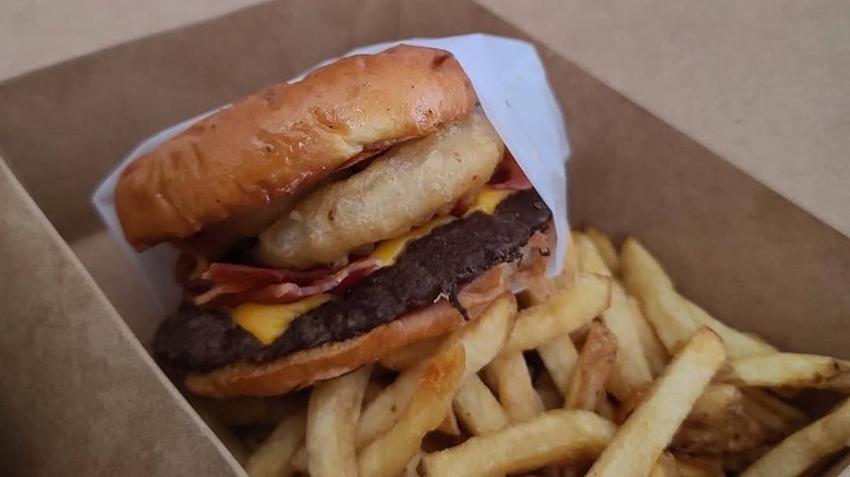 burger with onion ring and bacon with fries from Sideburns