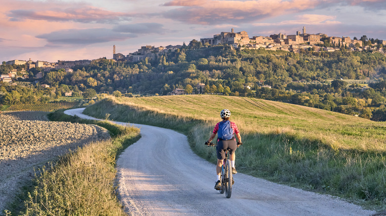 Woman biking towards Tuscany hill town in Italy