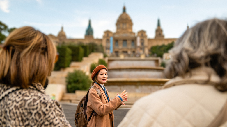 Tour guide in front of an ornate castle in Barcelona, Spain