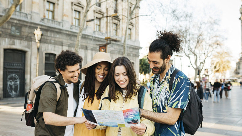 Four friends look at a map on a European street