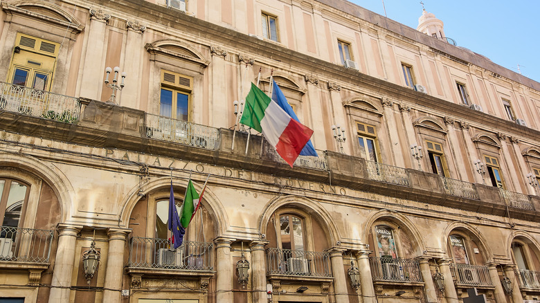 The Palazzo Minoriti in Catania, Sicily, Italy with the Italian flag at front.