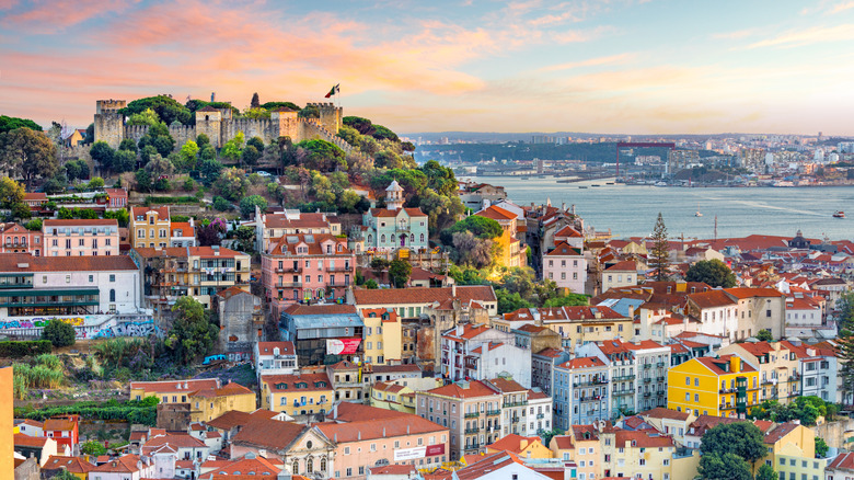 A view of a hillside in Lisbon, Portugal at sunset with the harbor in view.