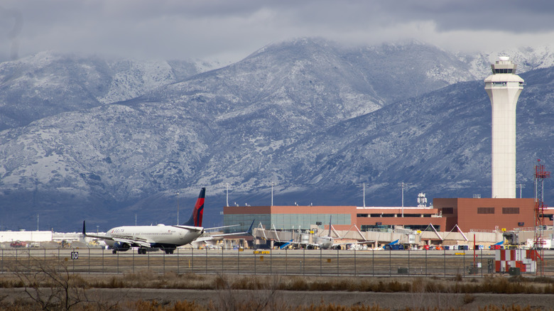 Delta plane on runway of Salt Lake City Airport with mountains and airport control tower in background