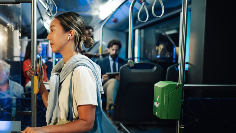 A woman standing near the front of a bus