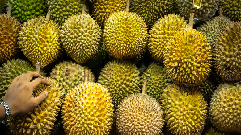 Hand placed over a pile of durian fruit