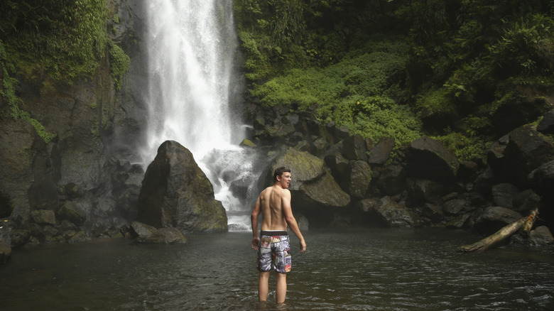 A person standing at the bottom of the powerful Father Falls at Dominica's Trafalgar Falls
