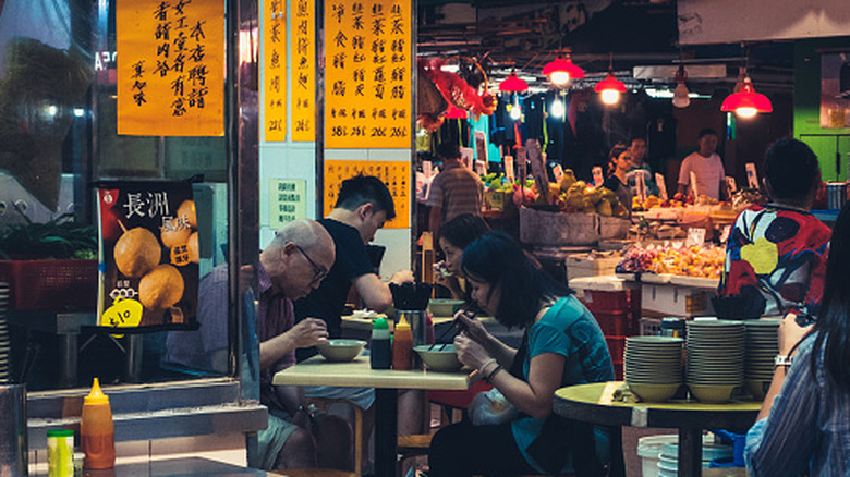 People eating in outdoor street food restaurant in Hong Kong at night