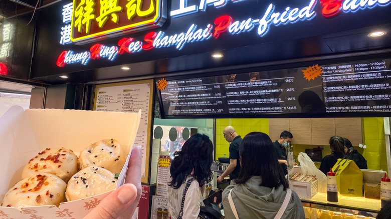 Man holding Shanghai Pan-fried Buns outside a popular Michelin-recommended street food store in Hong Kong