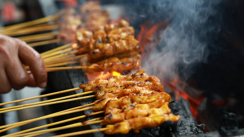 Close up of chicken satay being grilled on skewers in Malaysia