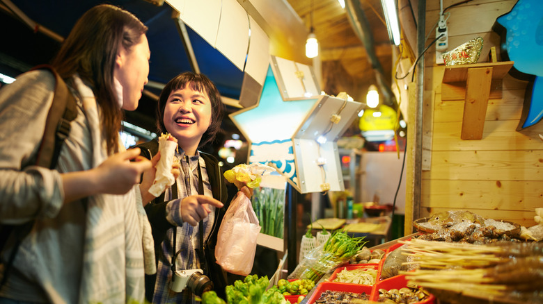 Shot of two young women eating food at a Taiwanese night market