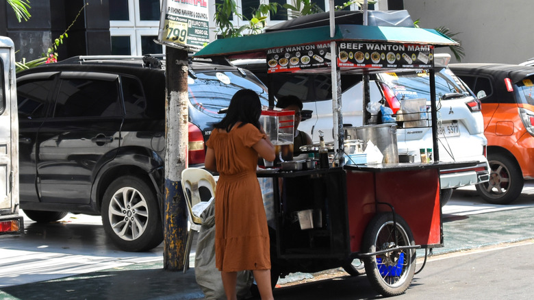 Woman buying food from a street vendor in the city of Manila.