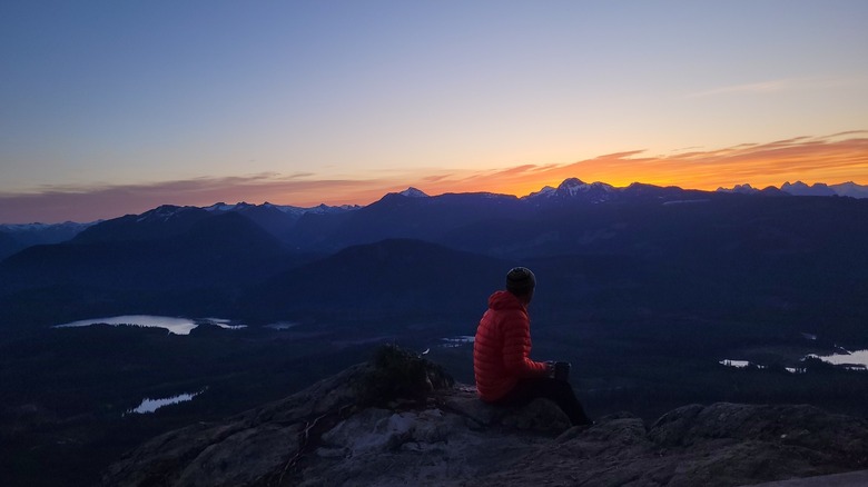 Hiker soaks up the sunrise on Walt Hill along Canada's Sunshine Coast Trail