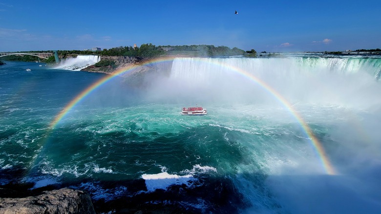 A rainbow arcs over a boat in the Niagara Falls