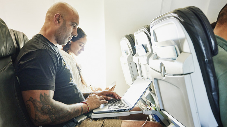 Couple using personal electronics on plane