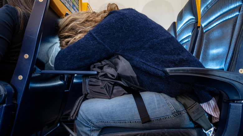Woman laying her head on plane tray table