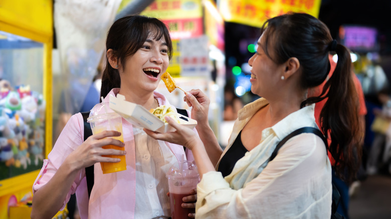 Two females enjoy food in a Taipei night market.