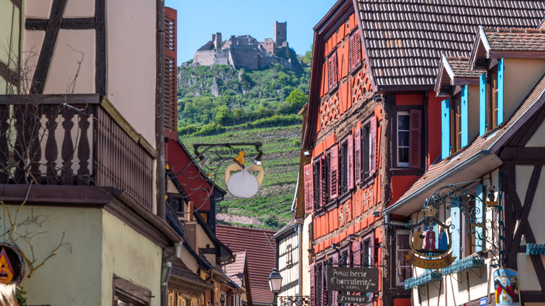 Hilltop castle visible between half-timbered buildings in France's Alsace region