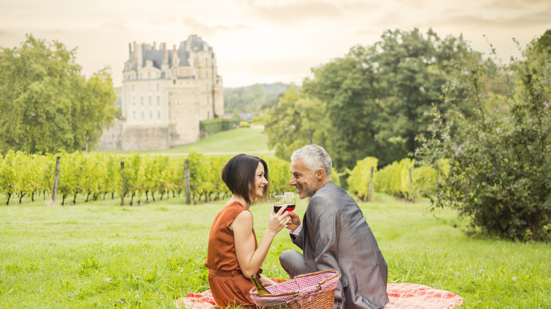 Couple drinking wine overlooking a vineyard and castle in France's Loire Valley