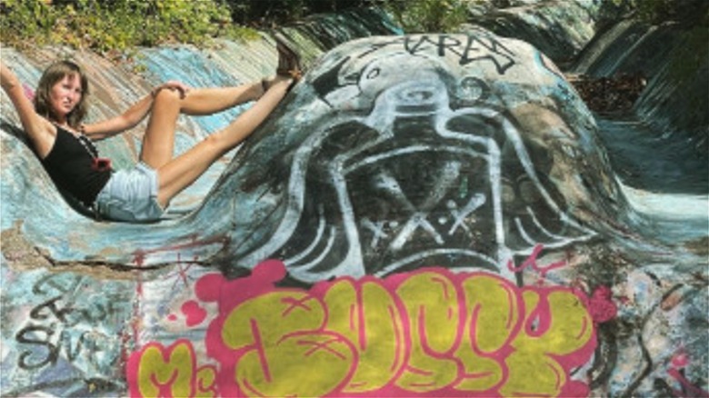 Young woman posing on the abandoned, graffitied concrete water slides at the abandoned Aqua Thrill Way park in Austin, Texas