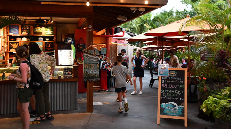 View of people strolling the downtown strip of Kailua-Kona on the Big Island, Hawaii, with stalls, outdoor dining tables, and plants
