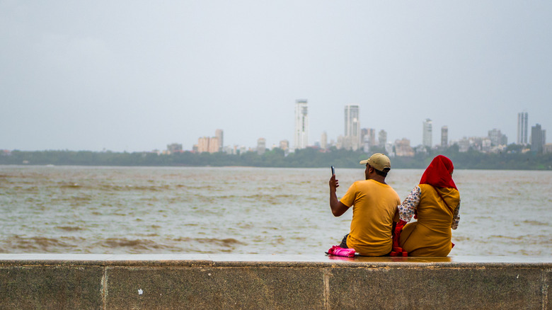 Man and woman sitting seaside in Mumbai