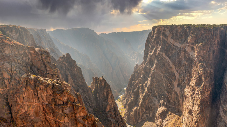 A river runs between towering cliffs at Black Canyon of the Gunnison National Park in Colorado.