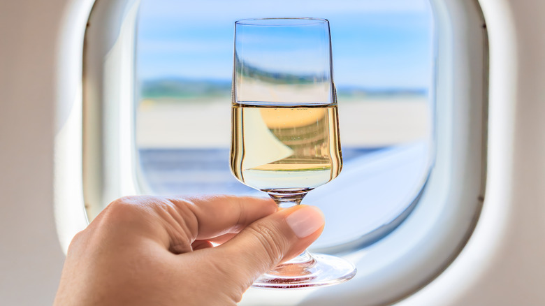 Man raising glass near airplane window