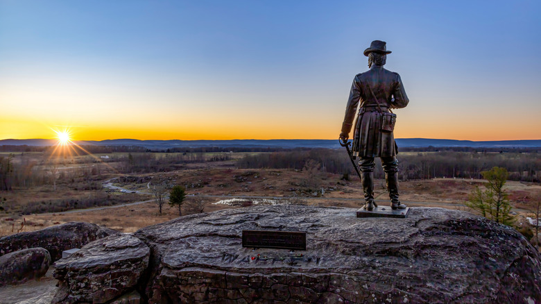 A sunset over Gettysburg Battlefield from Little Round Top with the statue of General Warren.