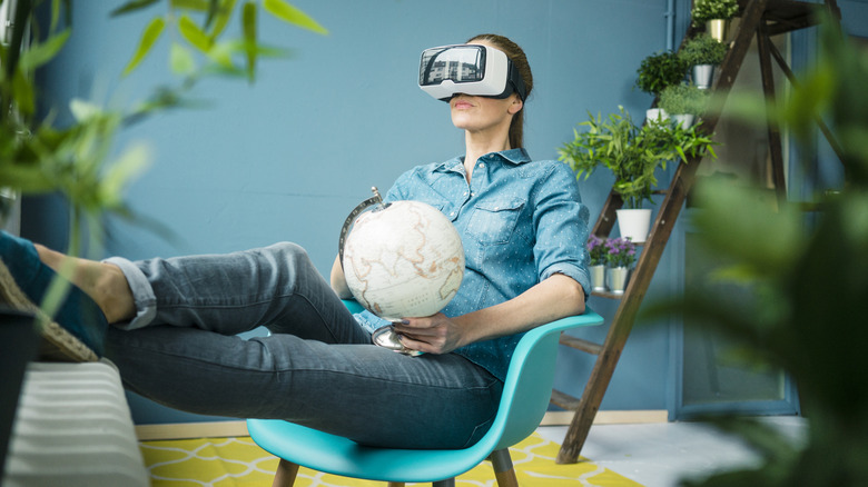 Seated woman wearing a virtual reality headset holding a globe in her lap