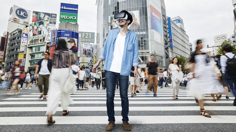 Man standing in Tokyo's busy Shibuya Scramble Crossing intersection wearing a virtual reality headset