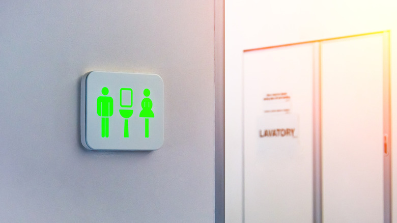 A green toilet sign on an airplane