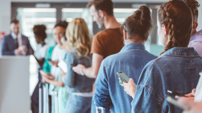 Passengers shown from behind as they stand in line to board a flight.