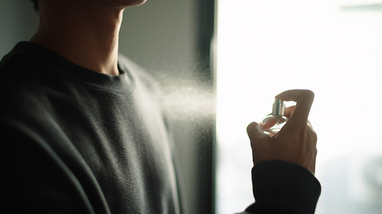 man sprays cologne on himself