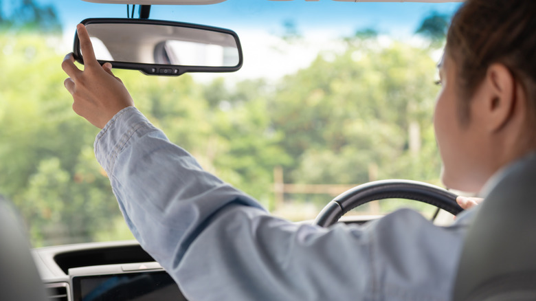 female driver adjusts the car rearview mirror