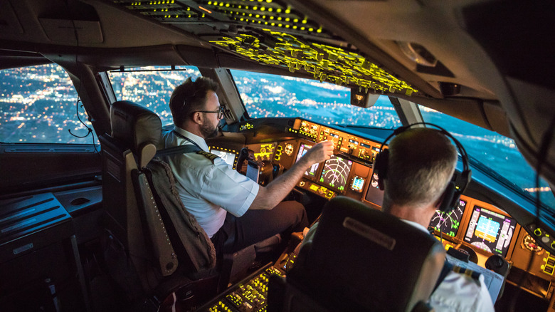 Pilots inside a lit up cockpit during a flight