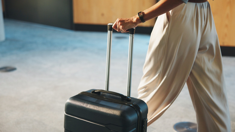 Passenger walking with a black suitcase