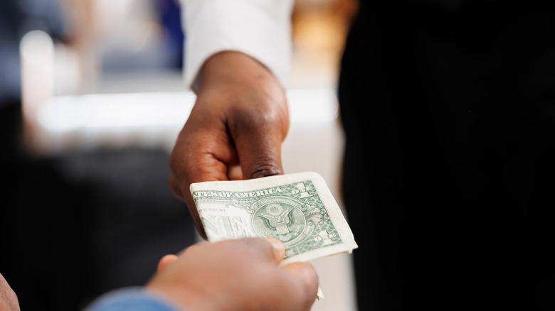 A worker accepts cash payment from a guest.