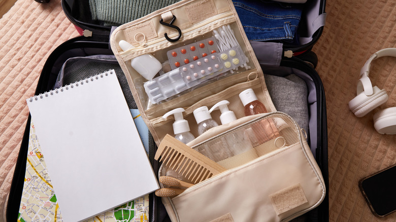 A toiletry kit packed with bottles of products, pills, and other grooming products