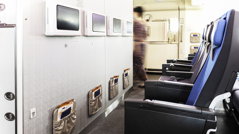 Interior view of the bulkhead row in a Singapore Airlines plane, with a flight attendant visible in the background