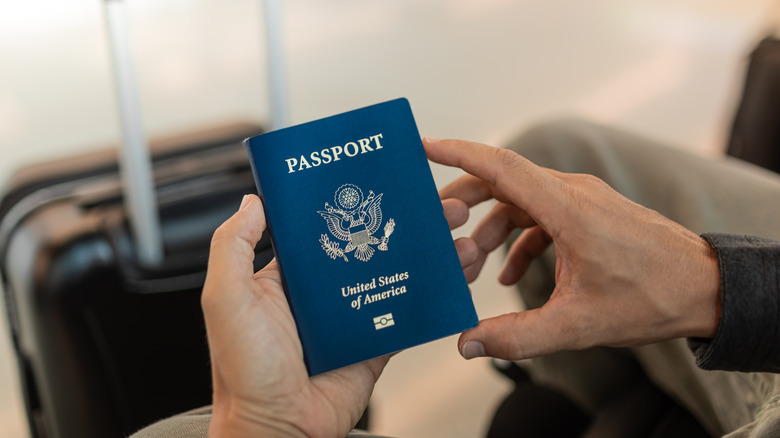 Someone holding a passport in front of a carry-on