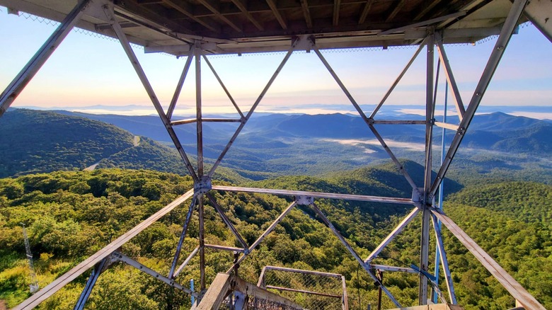 A sunrise view of green trees and the Blue Ridge Mountains framed by a steel structure