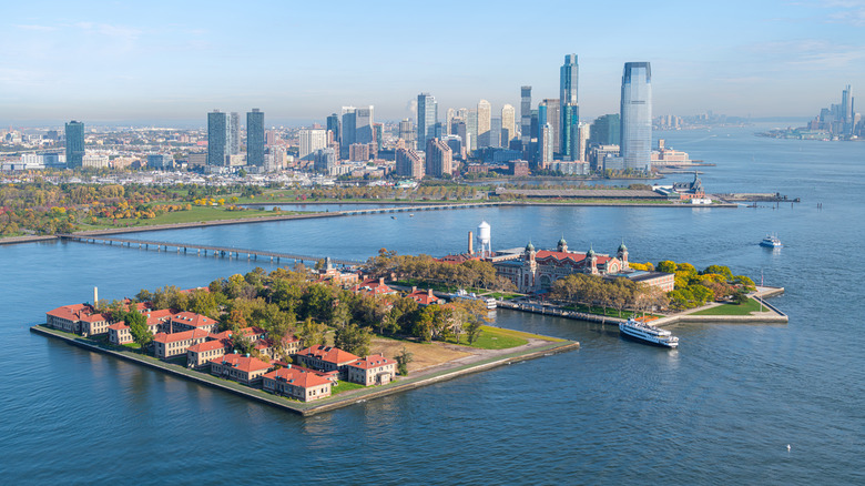 Historic immigration buildings on Ellis Island with the Jersey City skyline in the background, New York