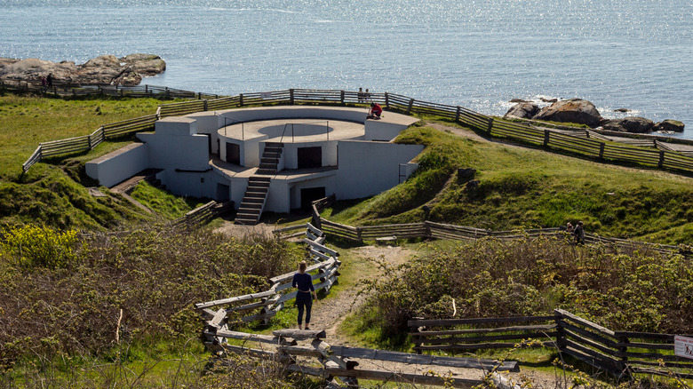 A former gun battery in Macauley Point Park surrounded by green grass with a shimmering lake in the background.