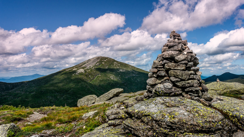 Rocks stacked in a pile on peak of hill in front of cloudy sky