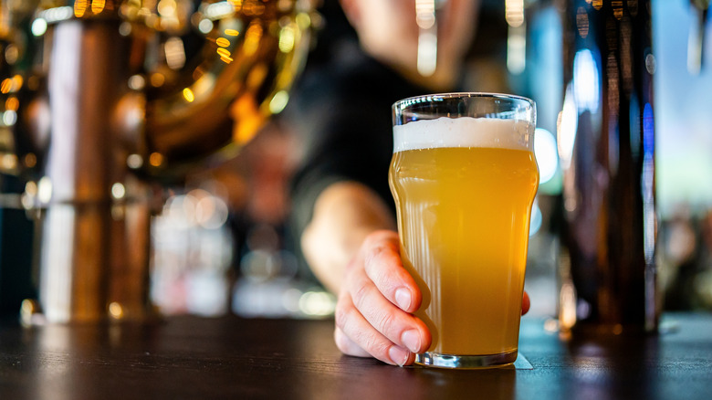 Bartender offering full glass of beer