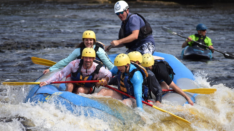 A group of people smiling on a whitewater raft in a river