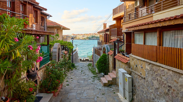 Narrow cobblestone walkway in old town area of Sozopol with sea in background