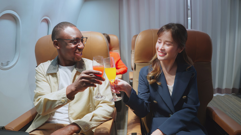 Two people drinking a cocktail on the plane