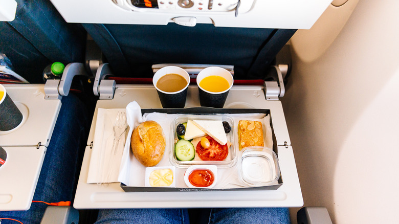 A meal on an airplane with orange juice and coffee